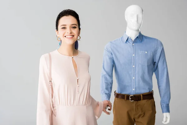 Beautiful smiling girl holding hands with mannequin isolated on grey — Stock Photo
