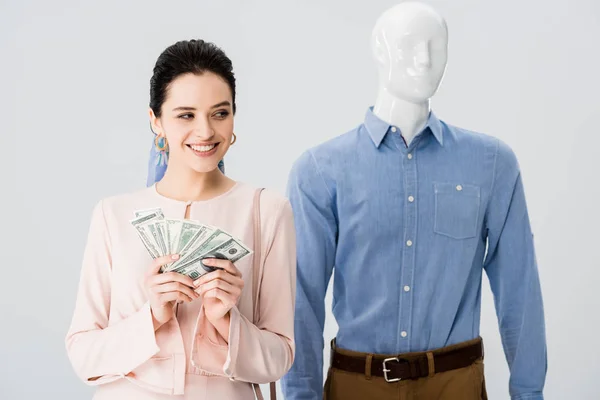 Beautiful smiling girl near mannequin holding money isolated on grey — Stock Photo