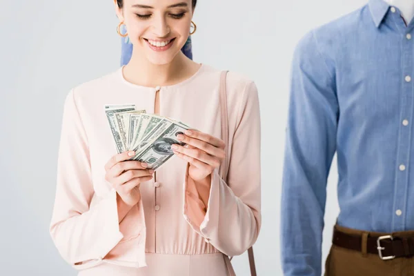 Beautiful smiling girl near mannequin counting money isolated on grey — Stock Photo