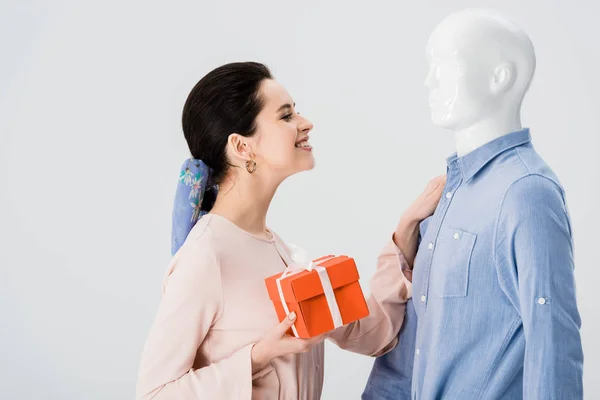 Bella ragazza sorridente con scatola regalo guardando manichino isolato su grigio — Foto stock