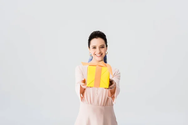 Schöne stylische junge Frau hält Geschenk und lächelt isoliert auf grau — Stockfoto