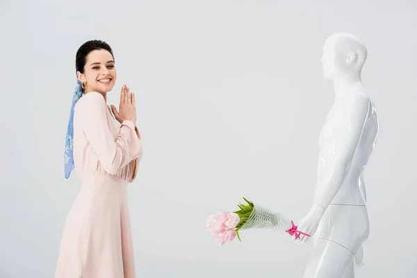 Schöne aufgeregte Mädchen und Schaufensterpuppe mit Blumenstrauß isoliert auf grau — Stockfoto