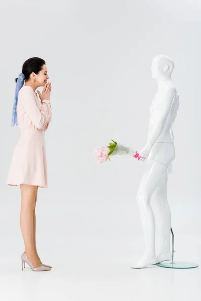 Beautiful excited girl and mannequin with flower bouquet isolated on grey — Stock Photo