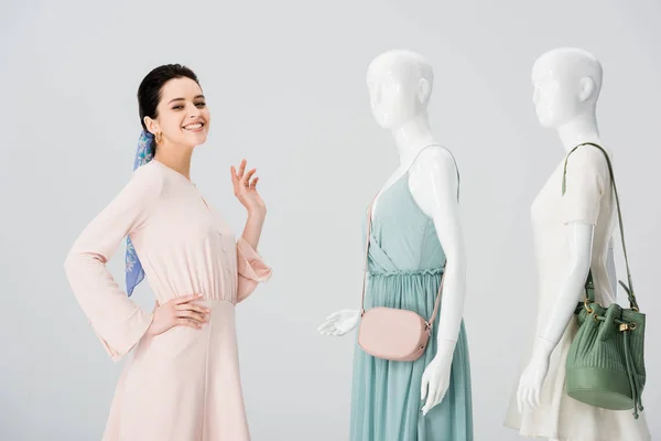 Bela menina feliz posando com manequins em vestidos isolados em cinza — Fotografia de Stock