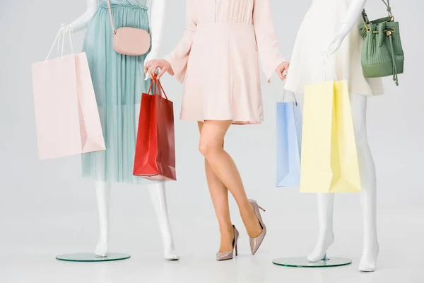 Vista cortada de mulher jovem com sacos de compras perto de manequins em cinza — Fotografia de Stock
