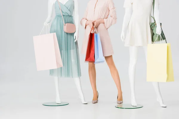 Vista cortada de mulher jovem com sacos de compras perto de manequins em cinza — Fotografia de Stock