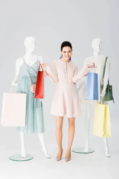 Beautiful happy girl with shopping bags near mannequins on grey — Stock Photo