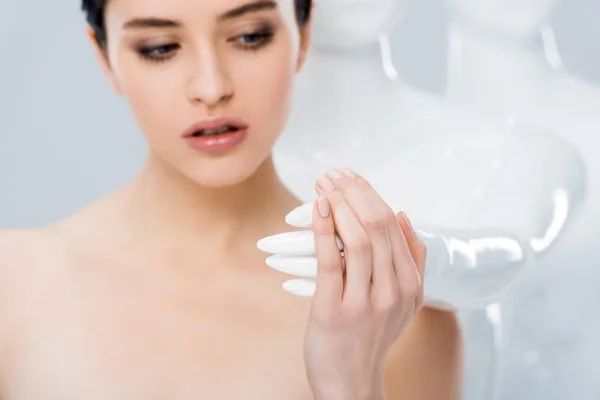 Hermosa chica desnuda sosteniendo la mano de maniquí blanco aislado en gris - foto de stock