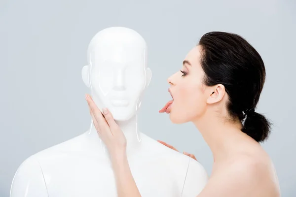 Beautiful young woman sticking out tongue near mannequin isolated on grey — Stock Photo