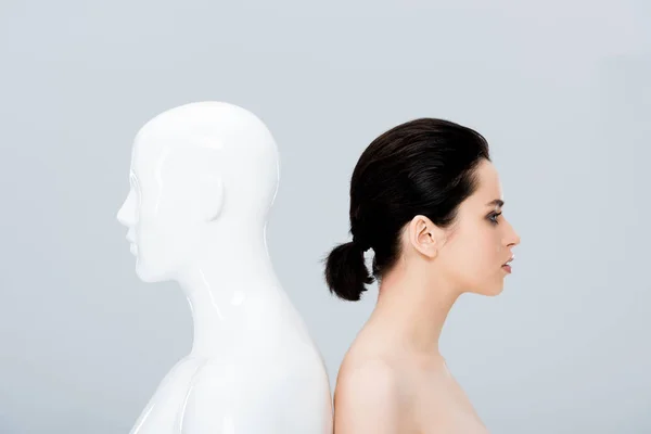 Beautiful naked young woman posing with mannequin isolated on grey — Stock Photo