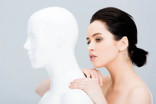 Attractive young woman posing with plastic mannequin isolated on grey — Stock Photo