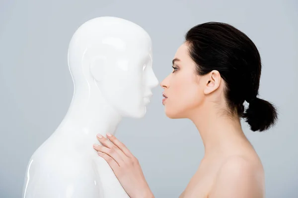 Beautiful young woman looking at plastic mannequin isolated on grey — Stock Photo
