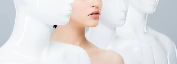 Panoramic shot of girl posing in row of mannequins isolated on grey — Stock Photo