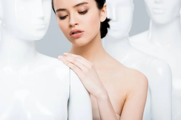 Beautiful young woman leaning hand on mannequin isolated on grey — Stock Photo