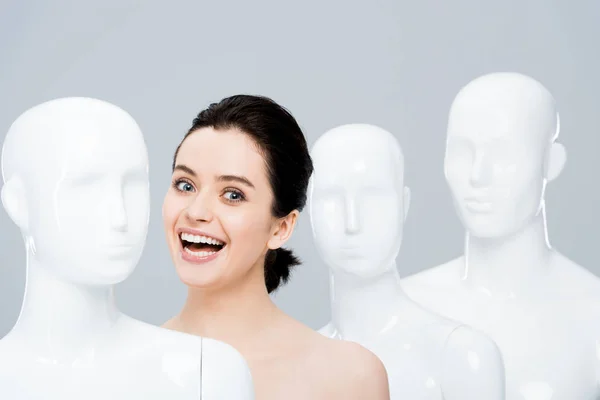 Красива щаслива дівчина позує біля манекенів ізольована на сірому — стокове фото