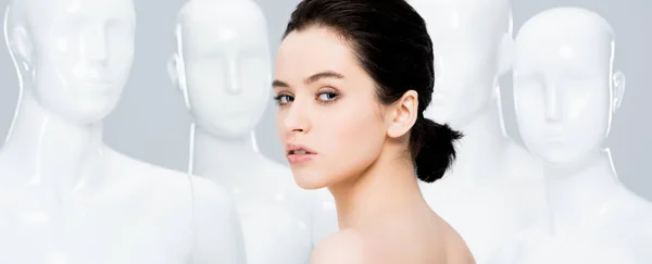 Panoramic shot of beautiful girl posing near mannequins isolated on grey — Stock Photo