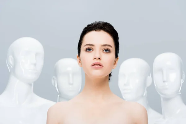 Bela menina nua posando perto de manequins isolados em cinza — Fotografia de Stock