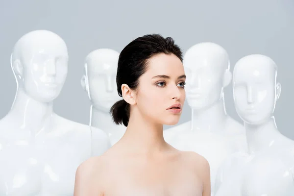 Beautiful nude girl posing near mannequins isolated on grey — Stock Photo