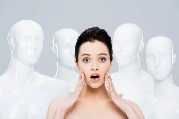 Beautiful surprised girl posing near mannequins isolated on grey — Stock Photo