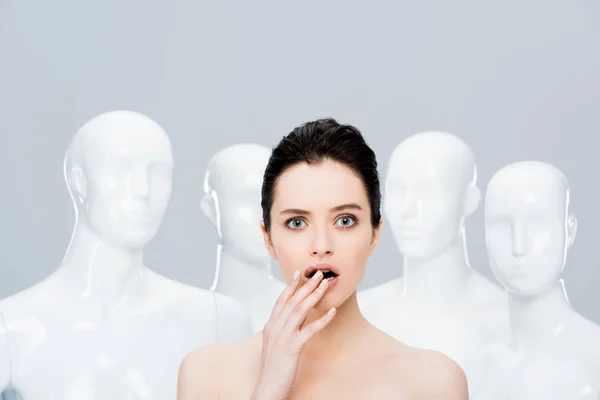 Beautiful surprised girl posing near mannequins isolated on grey — Stock Photo