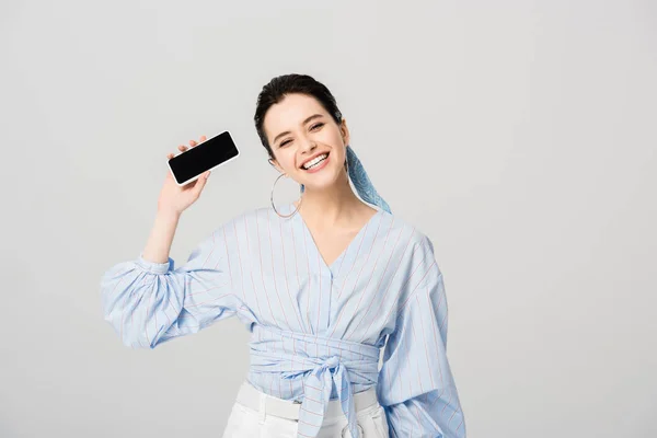 Schöne stilvolle Mädchen mit Halten Smartphone mit leerem Bildschirm isoliert auf grau — Stockfoto