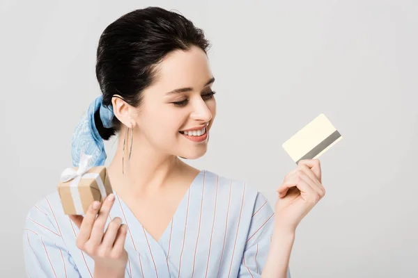 Красива стильна дівчина тримає подарункову коробку і кредитну картку ізольовано на сірому — стокове фото