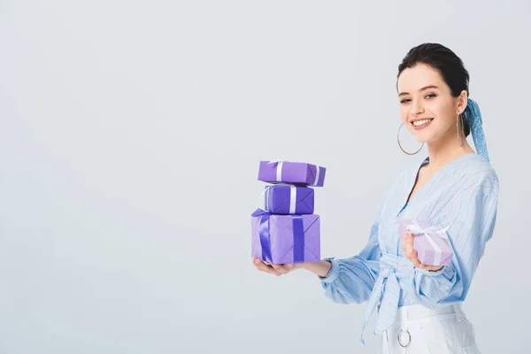 Schöne stilvolle Mädchen halten Geschenkboxen und lächeln isoliert auf grau — Stockfoto