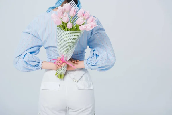 Back view of stylish girl with bouquet of tulips isolated on grey with copy space — Stock Photo