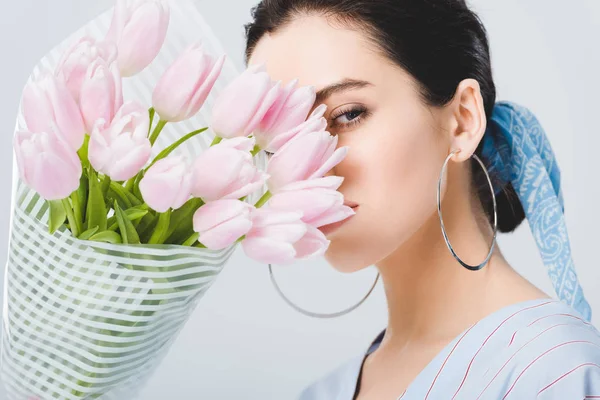 Beautiful stylish girl in earrings with bouquet of tulips isolated on grey — Stock Photo