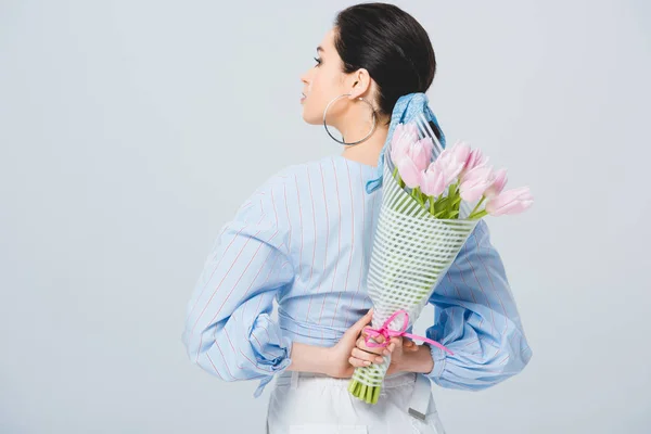 Vista posteriore di ragazza alla moda con bouquet di tulipani isolati su grigio — Foto stock