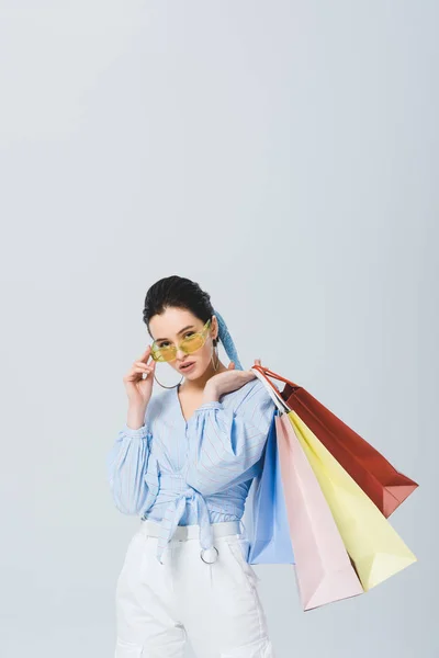 Beautiful stylish girl with shopping bags isolated on grey — Stock Photo