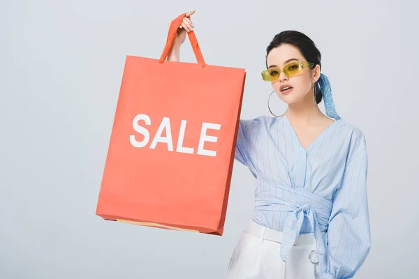 Bella ragazza elegante in possesso di shopping bag con parola di vendita isolato su grigio — Foto stock