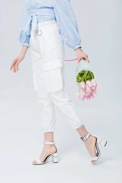 Partial view of stylish girl with bouquet of tulips on grey — Stock Photo