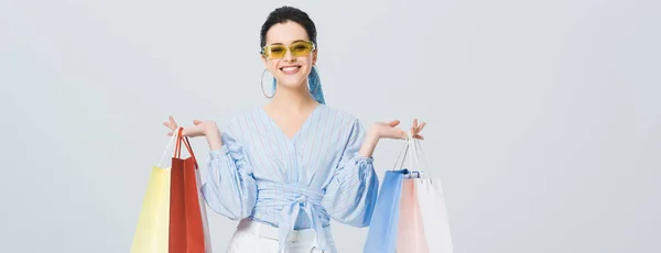 Panoramic shot of beautiful stylish girl with shopping bags smiling isolated on grey — Stock Photo