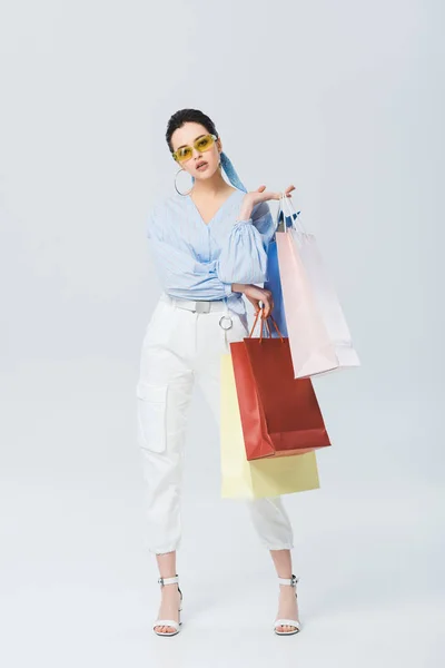 Hermosa chica elegante con bolsas de compras en gris - foto de stock