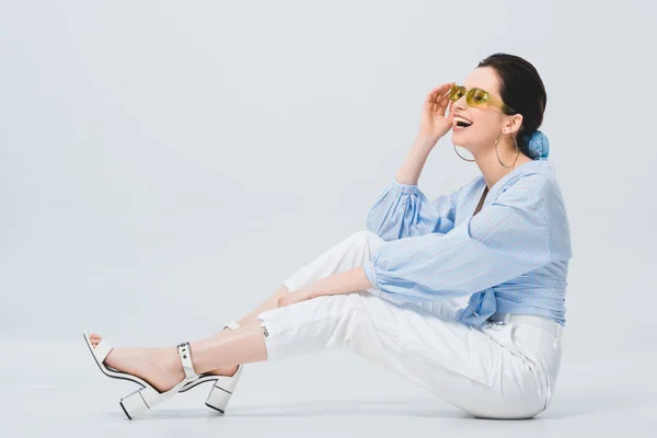 Bella ragazza elegante in occhiali da sole in posa e ridere sul grigio — Foto stock
