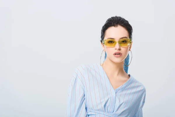 Hermosa chica con estilo en gafas de sol mirando a la cámara aislada en gris - foto de stock