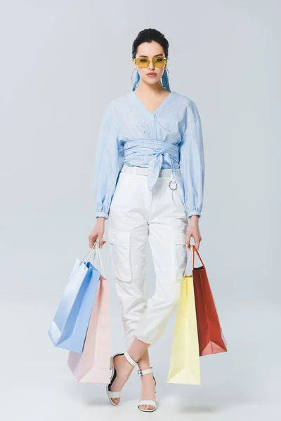 Beautiful fashionable girl with shopping bags on grey — Stock Photo