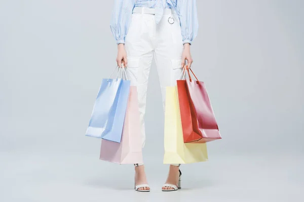 Vista recortada de la chica de moda con bolsas de compras en gris - foto de stock