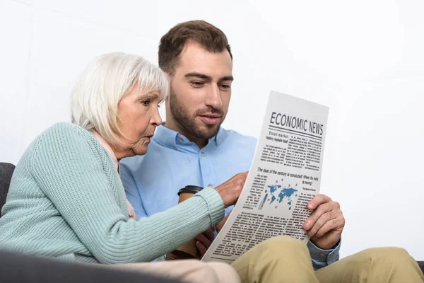 Uomo e madre anziana leggendo il giornale a casa — Foto stock