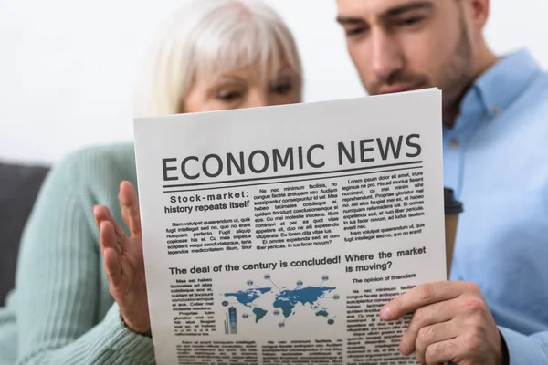 Selective focus of man and senior mother reading newspaper at home — Stock Photo