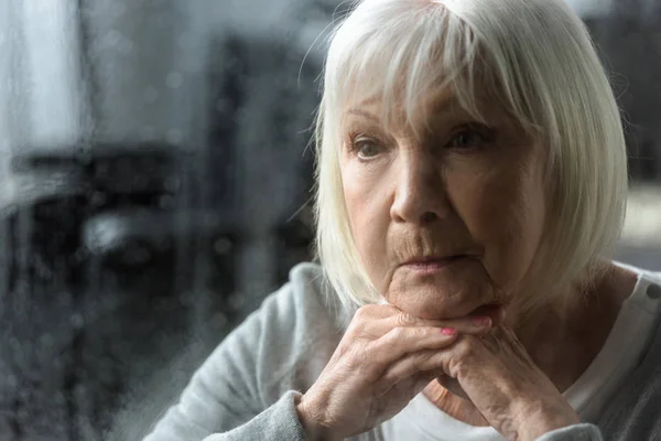 Сумна старша жінка з сірим волоссям дивиться геть — стокове фото