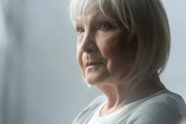 Mujer mayor pensativa con el pelo gris mirando hacia otro lado - foto de stock
