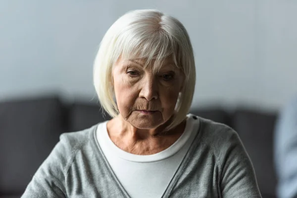 Nachdenkliche Seniorin mit grauen Haaren blickt nach unten — Stockfoto