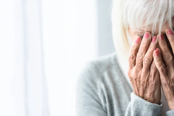 Vista parziale di piangere donna anziana che copre il viso con le mani — Foto stock