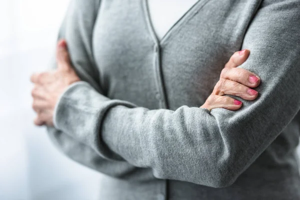 Partial view of senior woman with crossed arms at home — Stock Photo