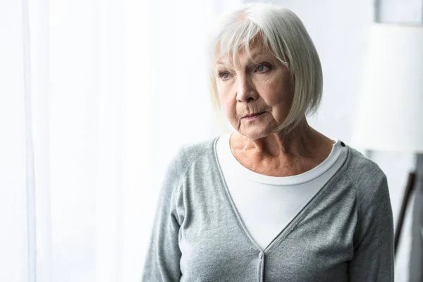 Nachdenkliche Seniorin in grauer Strickjacke schaut weg — Stockfoto