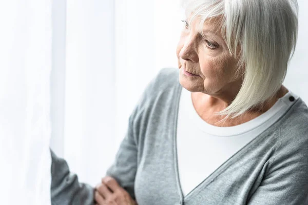 Nachdenkliche Seniorin mit grauen Haaren schaut zu Hause weg — Stockfoto