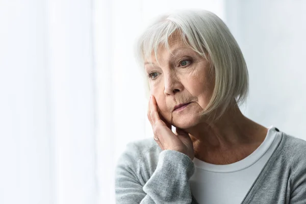 Nachdenkliche Seniorin mit grauen Haaren schaut zu Hause weg — Stockfoto