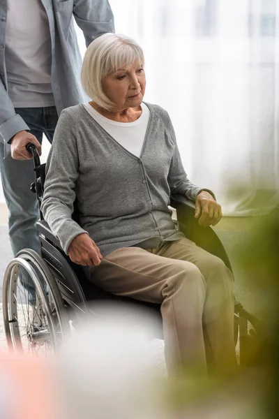 Cropped view of man carrying disabled mother on wheelchair — Stock Photo